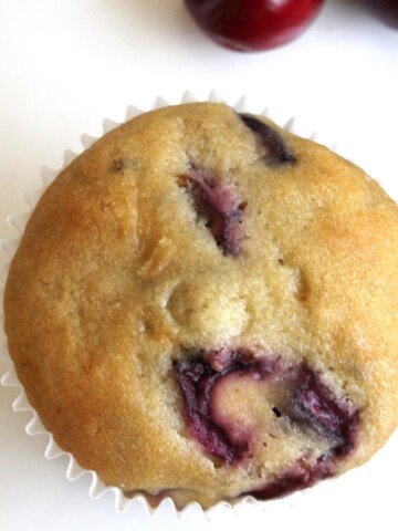 Overhead view of one big cherry muffin on a white plate.