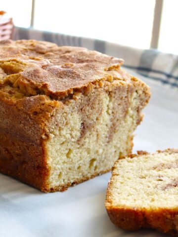 Sliced cinnamon bread on parchment paper in a sunny venue.