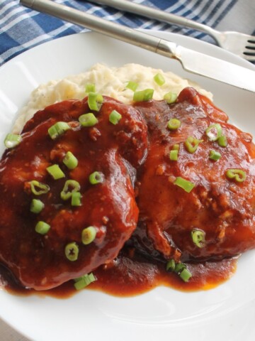 Saucy BBQ chicken over mashed potatoes, sprinkled with chopped green onion.