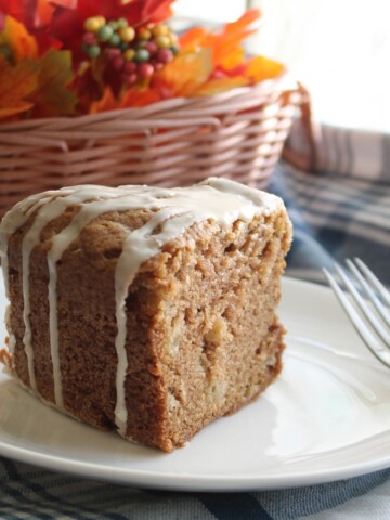 Slice of cake full of apples, drizzled with a sweet maple glaze.