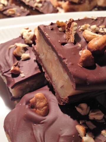 Stacks of chocolate toffee sprinkled with toasted pecans.