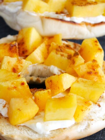 Close up of a toasted bagel with cream cheese and chopped peaches.