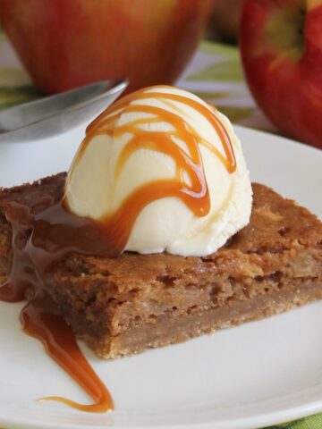 Close up of apple squares with a scoop of vanilla ice cream, drizzled with caramel.