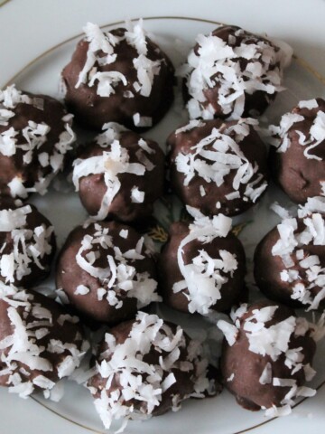 Chocolate bon bons on a plate, sprinkled with coconut.