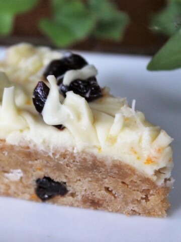 Blondie with cream cheese frosting on a white plate.