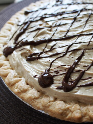 Close up of a peanut butter pie in a butter crust with a drizzle of chocolate across the top.