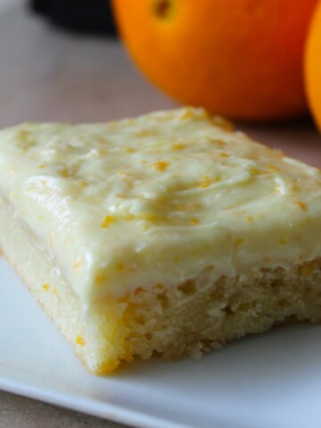 Rich orange bar with creamy frosting, sprinkled with orange zest.
