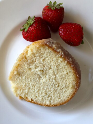 Slice of pound cake on a white plate with strawberries.
