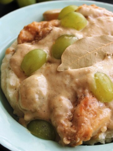 Close up of chicken smothered in wine gravy over mashed potatoes.