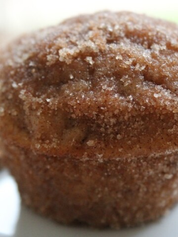 One Doughnut muffin on a tray with a couple of cinnamon sticks.
