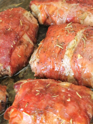 Chicken thighs wrapped in prosciutto in the baking pan.