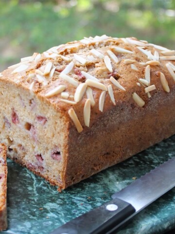 A cut loaf of strawberry bread on a green marble.