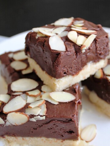 Stack of shortbread bars, with a thick layer of fudge and sprinkled with sliced almonds.
