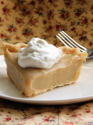 Slice of luscious butterscotch pie with a dollop of whipped cream on top.