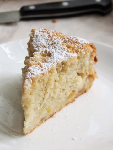 Slice of apple cake sprinkled with powdered sugar.