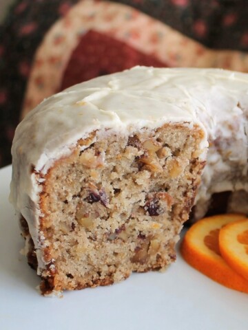 Half of a cranberry orange bundt cake on a white pedestal.