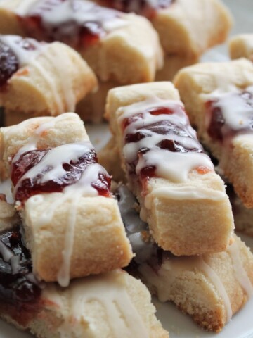Close up of sliced ribbon cookies stuffed with jam and drizzled with a light glaze.