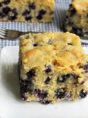 Slice of blueberry cornbread bursting with blueberries.