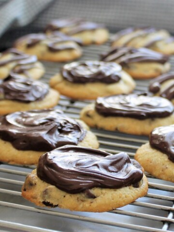 Orange cookies dipped in chocolate ganache on a cookie rack.