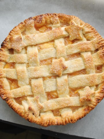 Lattice peach pie just out of the oven on parchment paper.