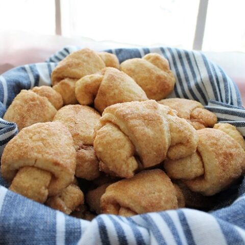 Ukrainian Scuffles (small twisted pastries) in a basket with a blue-striped cloth.