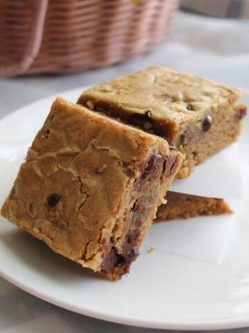 Squares of blondies leaned against each other on a white plate.