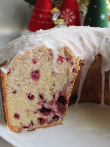 Vanilla Raspberry pound cake with a couple of slices out on a white plate.