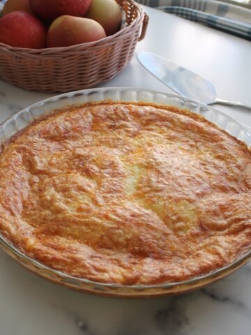 A full ham and cheese quiche on a marble slab.