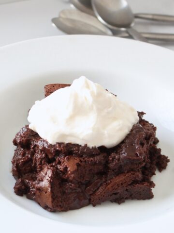 A giant spoonful of flourless chocolate cake, rich and moist, in a wide-rimmed white bowl.