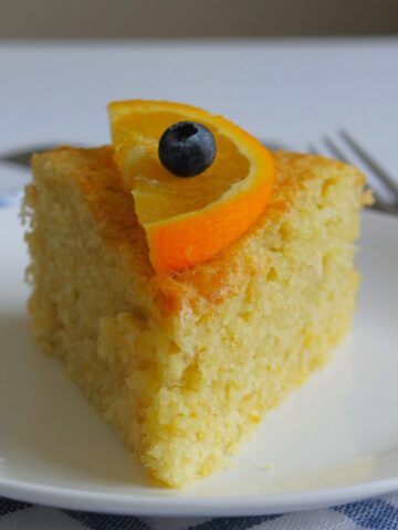 Overhead photo of a slice of olive oil cake on a white plate.