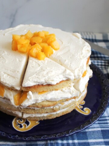 Whole 4 layer peach cake with a slice cut out.