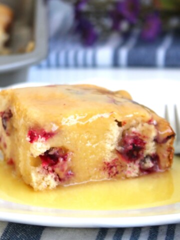 Slice of Cranberry Cake with Warm Butter Sauce on a white plate.