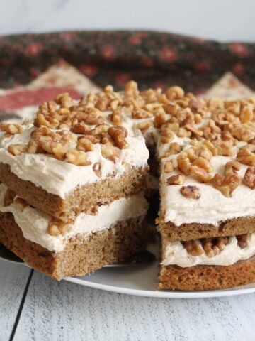 Whole Walnut Espresso Cake with Buttercream Frosting with a slice out of it on a white plate.