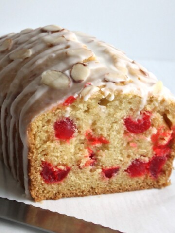 Front view of a cherry almond loaf cake full of bright red cherries.