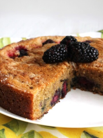 Blackberry Lime cake with a couple of slices cut from it. Fresh blackberries on top of the cake.